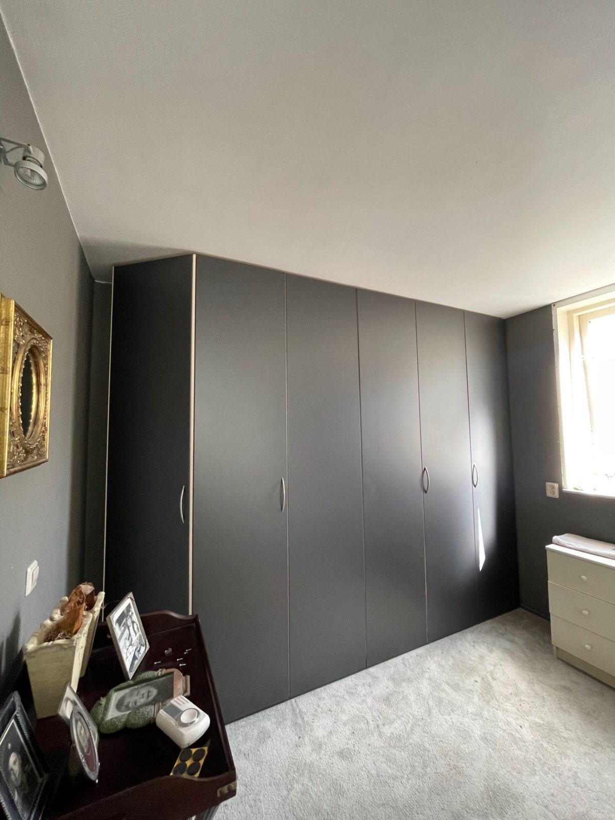 Built-in wardrobe with grey fronts in an attic room, wrapped