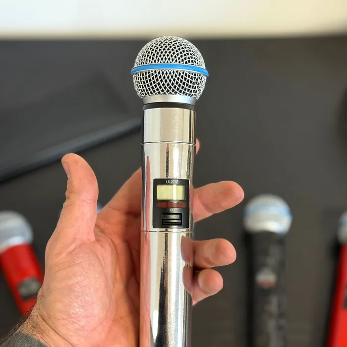 Hand holding a wireless Shure microphone wrapped in mirror chrome