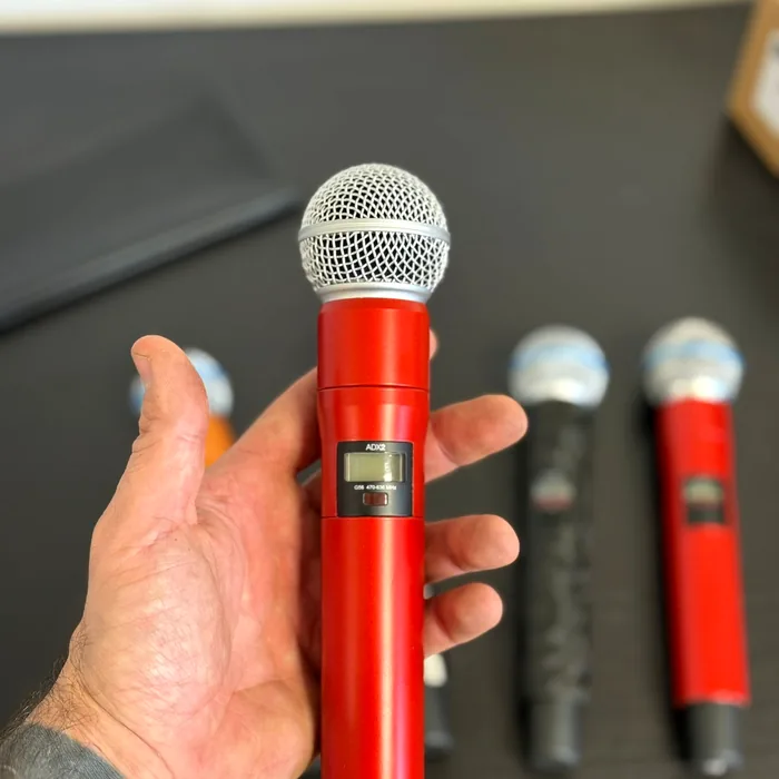 Hand holding a wireless Shure microphone wrapped in high-gloss red