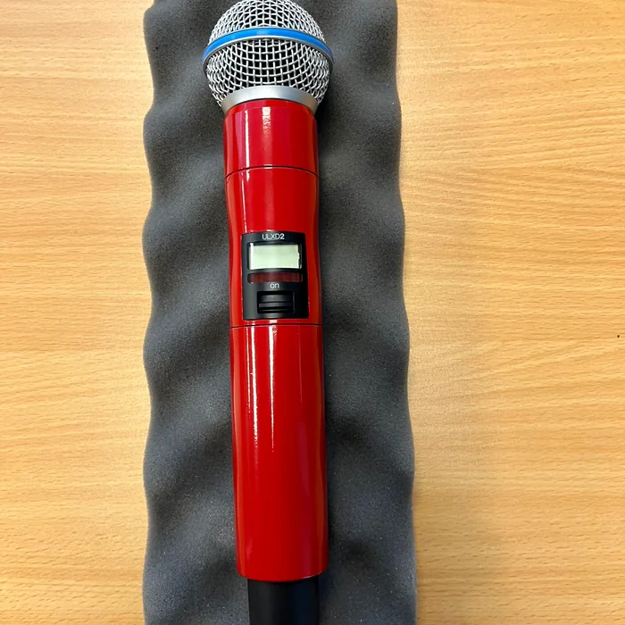 Wireless Shure microphone wrapped in high-gloss red, on grey foam
