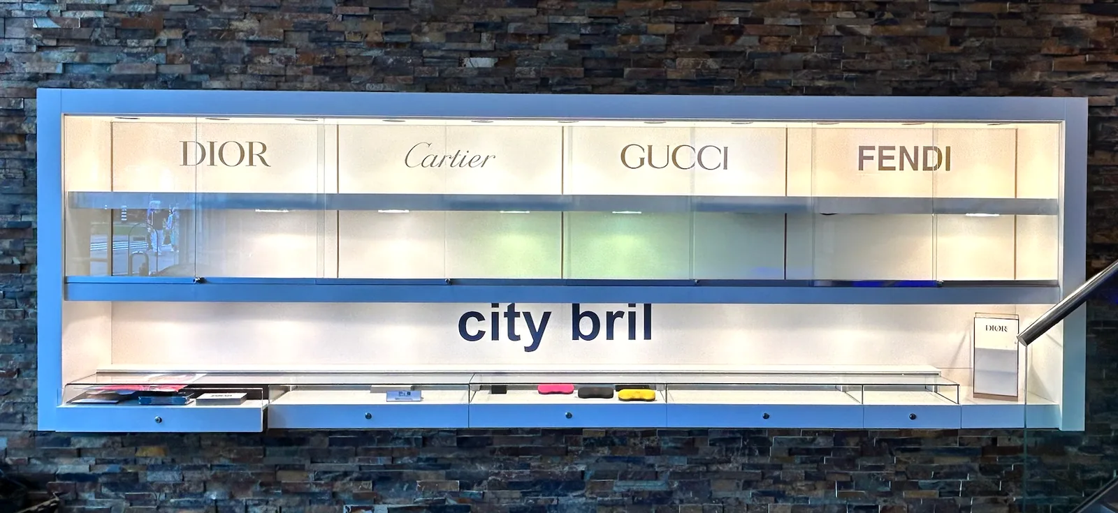 After: white display wall with the brand names Dior, Cartier, Gucci, Fendi and city bril