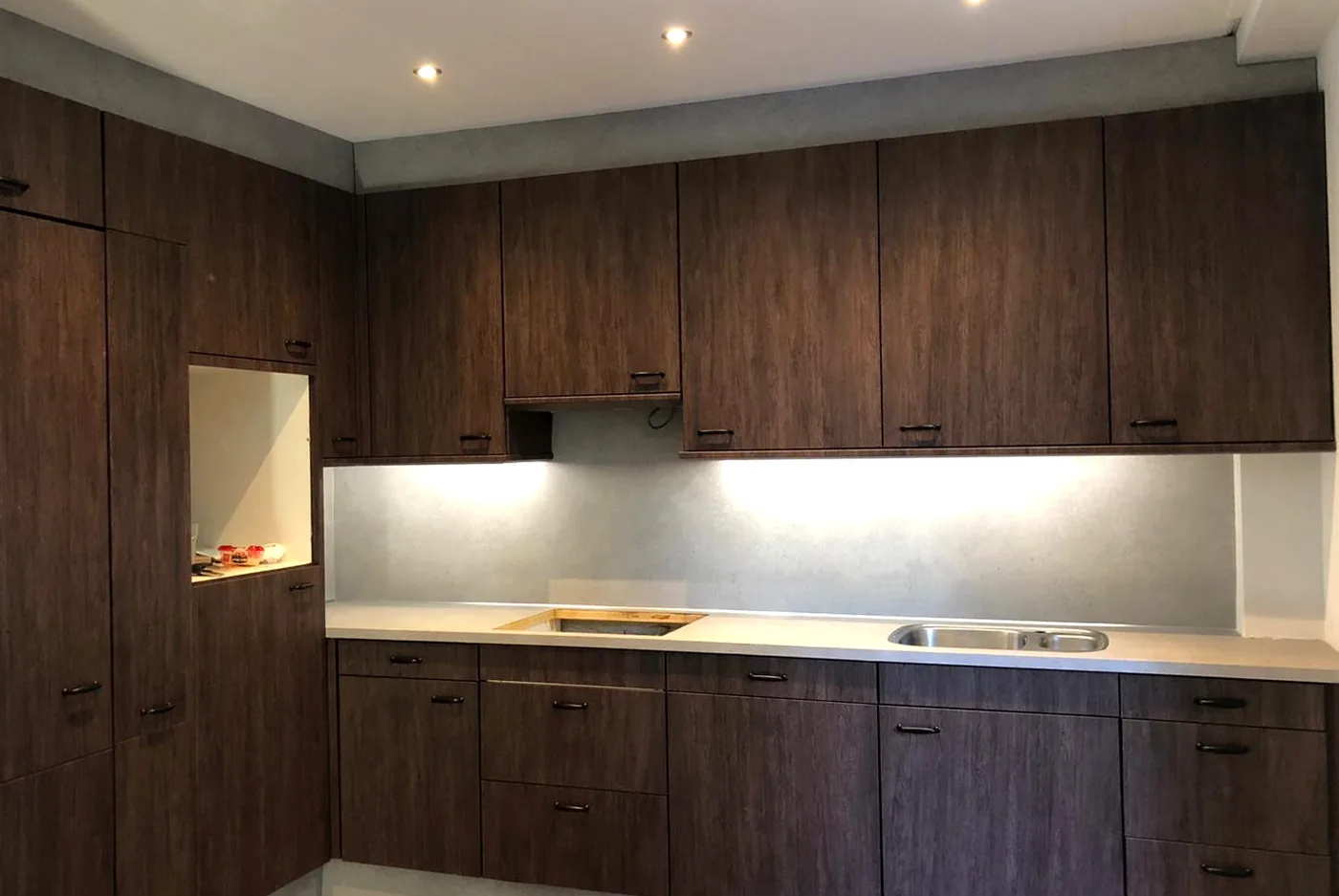 After: kitchen with dark woodgrain fronts and a light concrete-look worktop and splashback