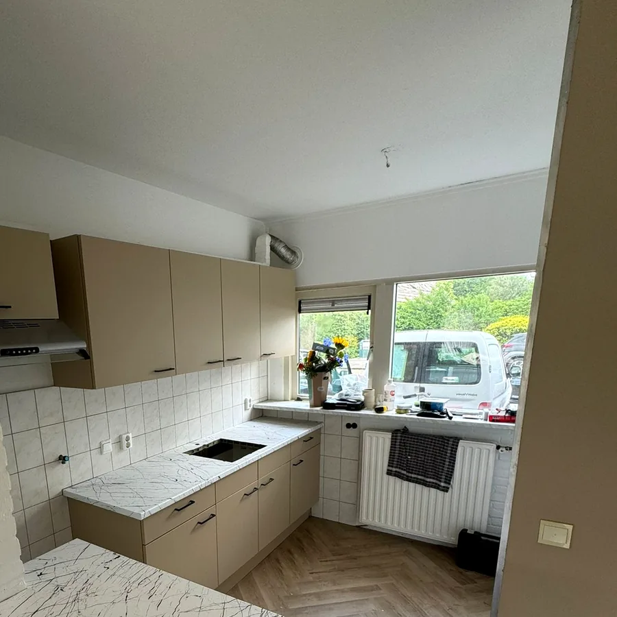 Overview of the taupe kitchen with the peninsula in a white marble look