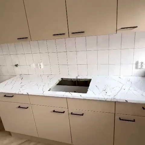 Kitchen with taupe wrapped fronts and a white marble-look worktop