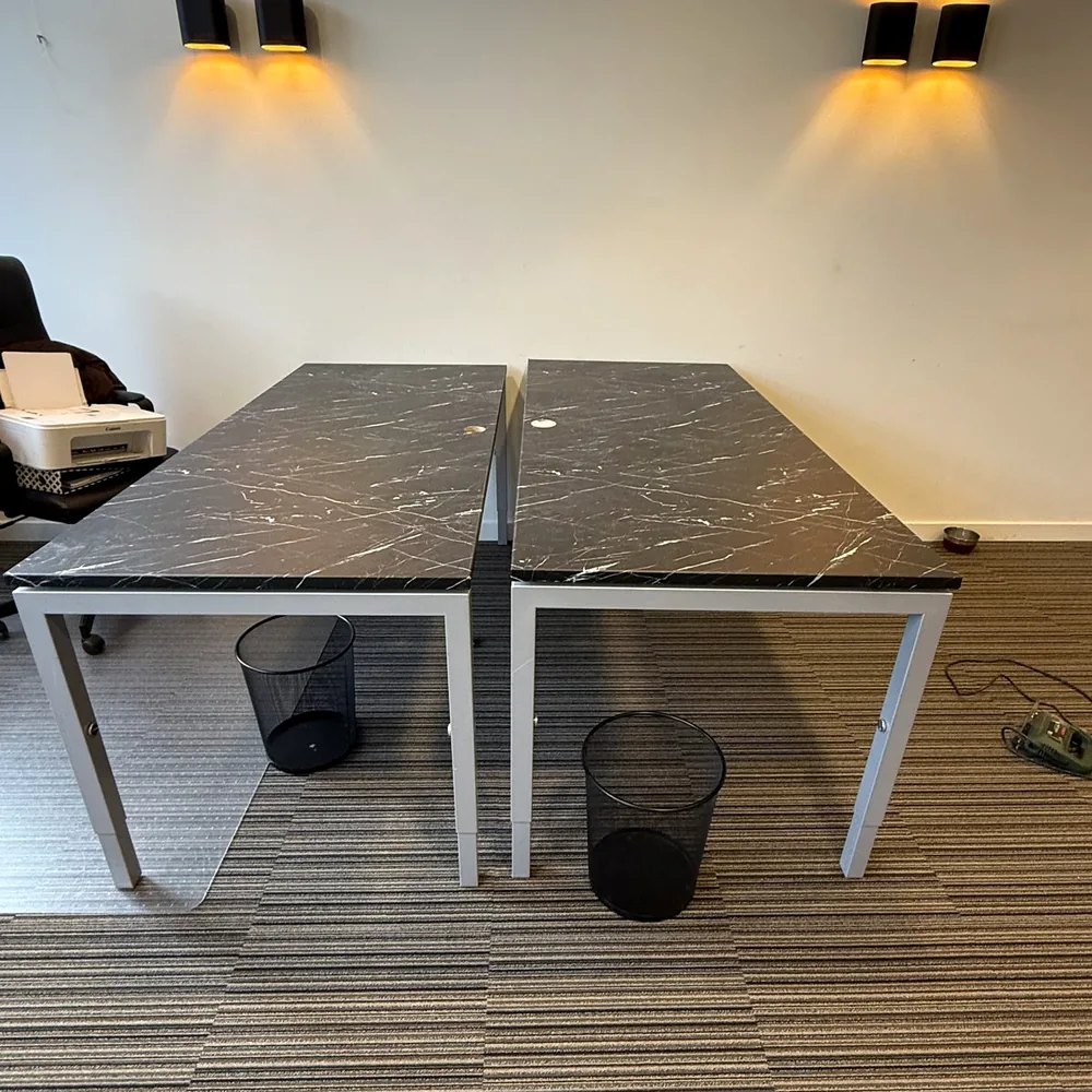 Two office desks with tops wrapped in a black marble look