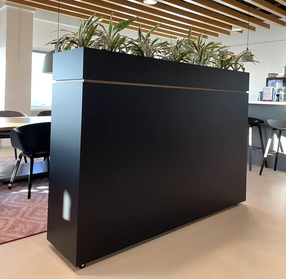 Room divider with a planter in an open office, wrapped in matt black by WRPPN