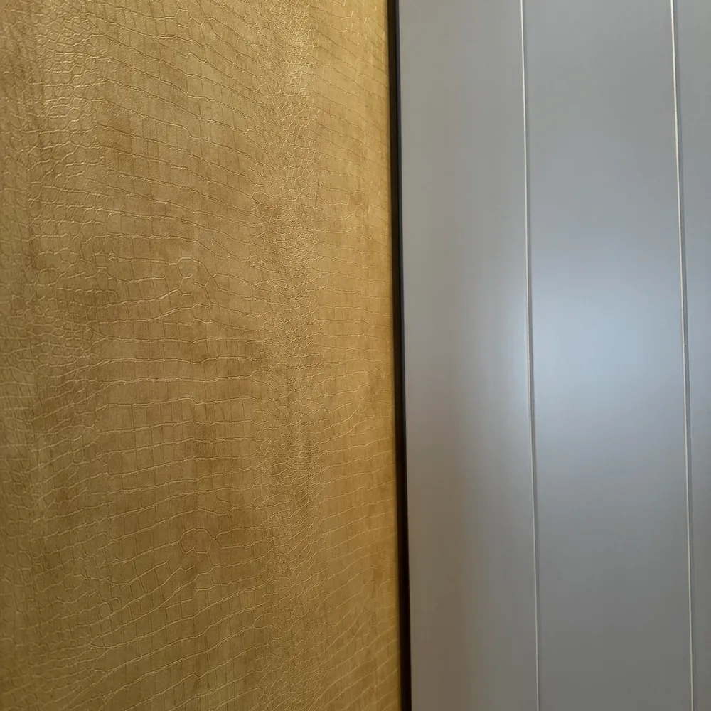 Close-up of the beige leather look with a gold sheen next to a white cabinet door