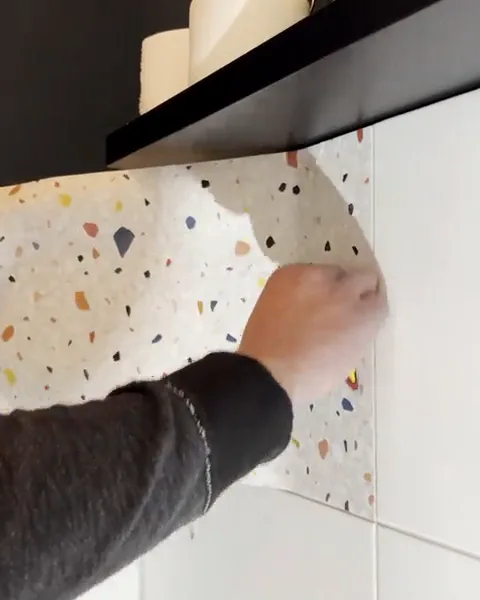 Terrazzo film is smoothed onto the tiles under the shelf