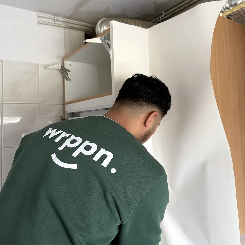 A fitter in a WRPPN sweater applies white film to a wall