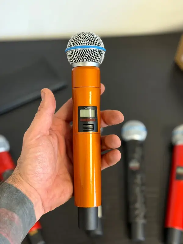 Hand with a microphone in metallic orange