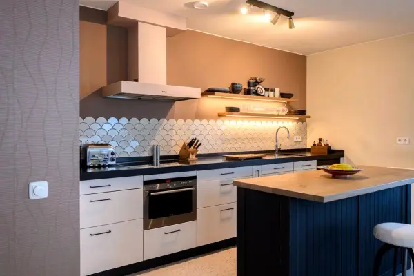 Kitchen with light pink wrapped fronts and extractor hood, next to a dark island
