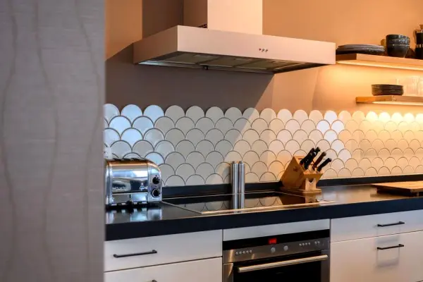 Cooking wall with white scalloped tiles and a black worktop