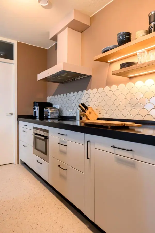 Kitchen wall with a light pink wrapped extractor hood and open shelves