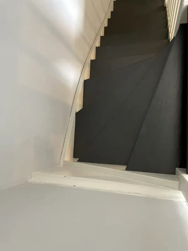Stairs with black treads between white walls, from below