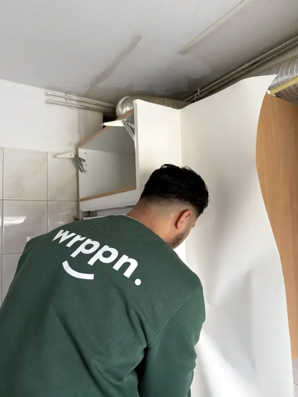 A fitter in a WRPPN sweater applies white film to a wall