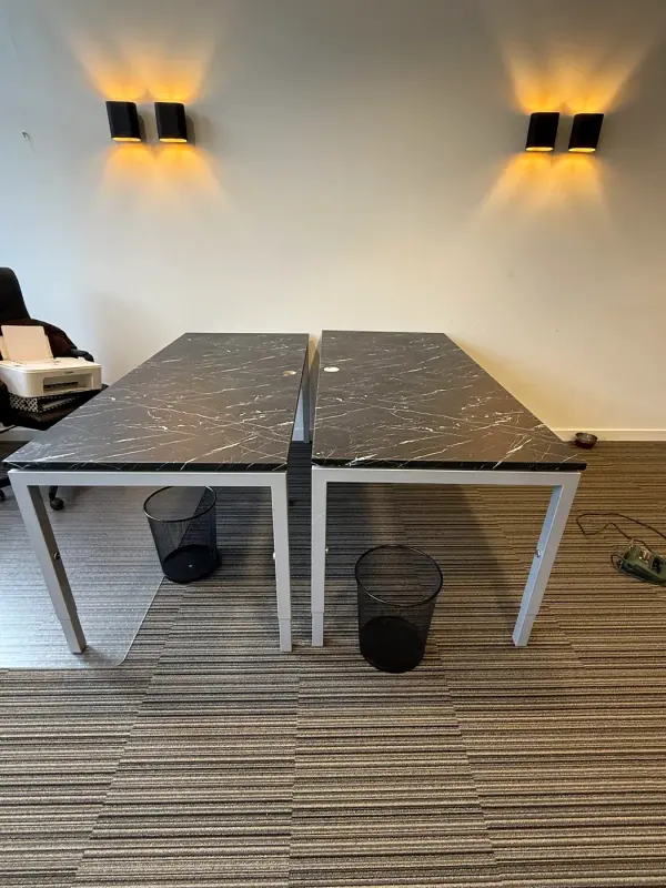 Two desks with black marble-look tops under wall lights