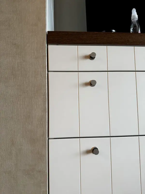 White chest of drawers next to a side panel in a beige leather look