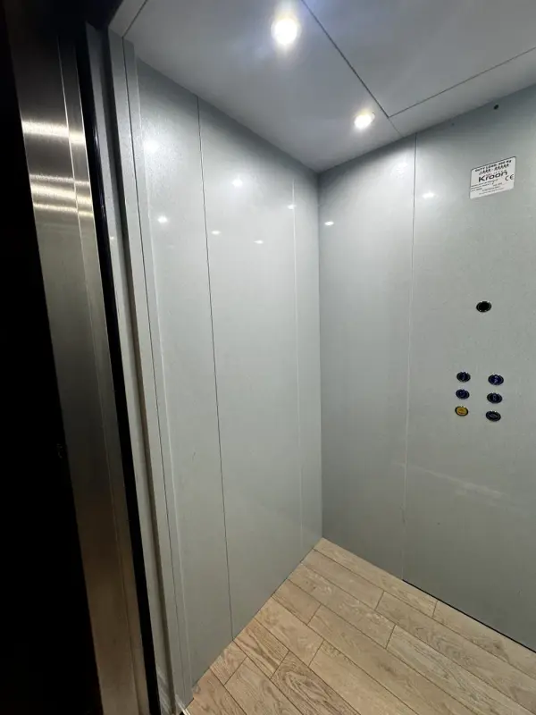 Before: grey lift walls with the control panel, at an angle