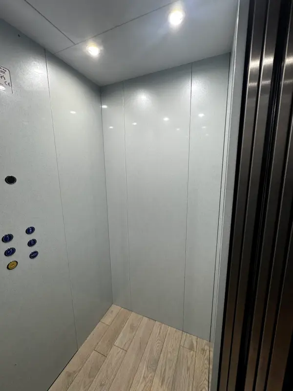 Before: grey lift wall with buttons, from the side