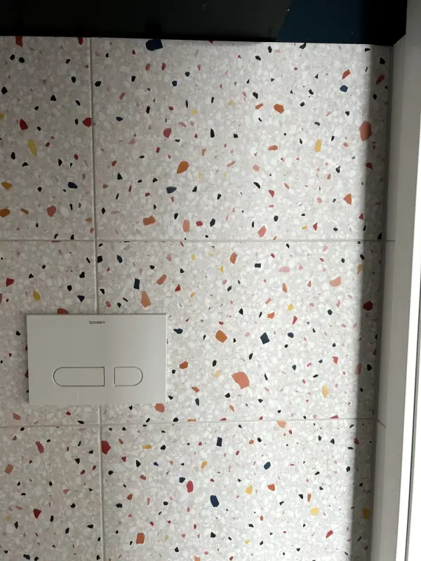 After: tiled wall in a terrazzo look with a white flush plate