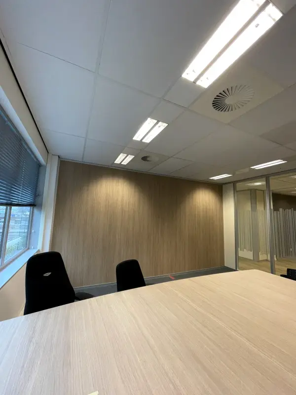 Meeting room with a light wood-look wall behind the table
